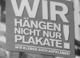 Plakat: Wir hängen nicht nur Plakate, wir kleben auch Aufkleber